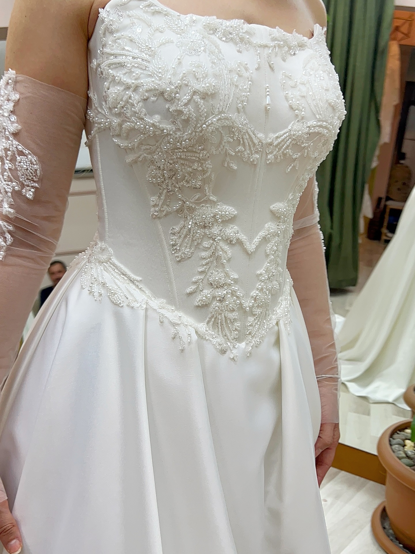 Yakın çekimde gelinliğin dantel ve boncuk işlemeleri, korseli yapı ve bel hattındaki detaylarla lüks ve zarif işçilik öne çıkıyor.