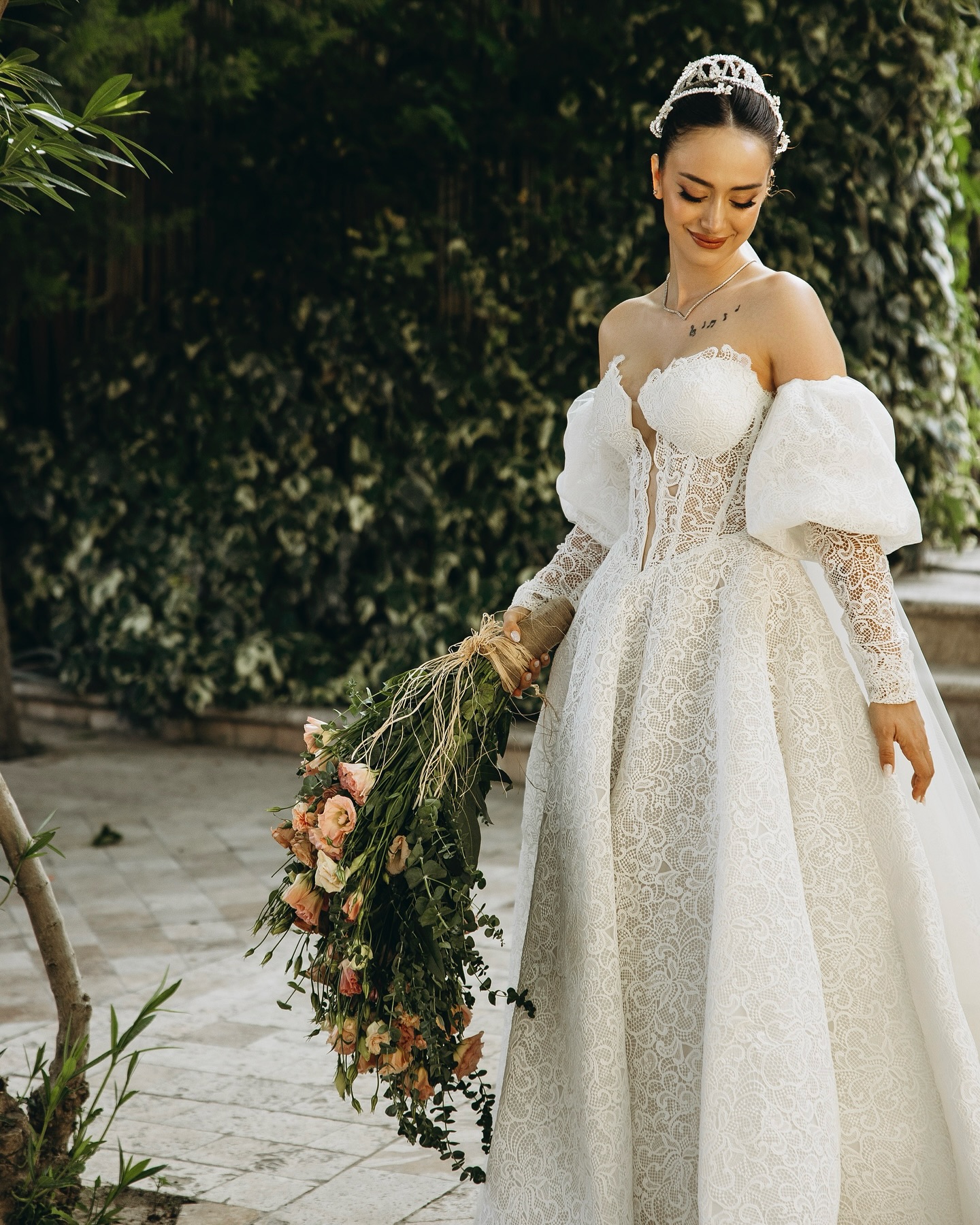 Korsaj detaylı, dantel işlemeli omuzdan düşük A kesim gelinlik giyen gelinin tam boy fotoğrafı