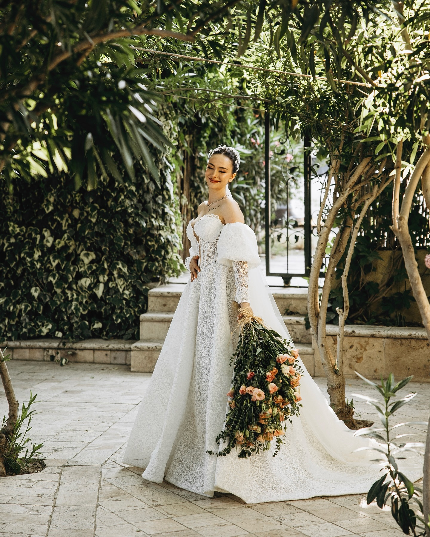 Uzun duvaklı, dantel A kesim gelinlik giyen gelinin bahçede tam boy konsept fotoğrafı