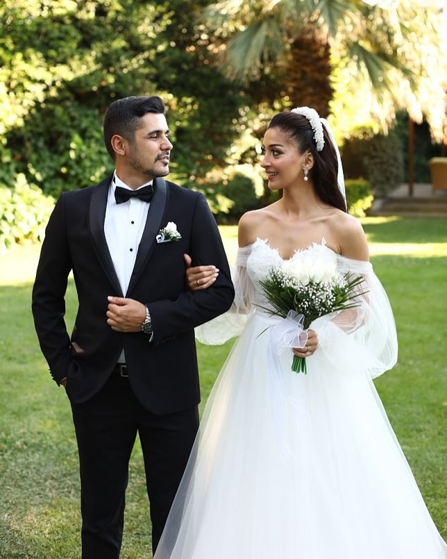  A kesim romantik gelinlik ve düşük omuz yaka detayıyla bahçe konseptinde gelin-damat yürüyüş pozu