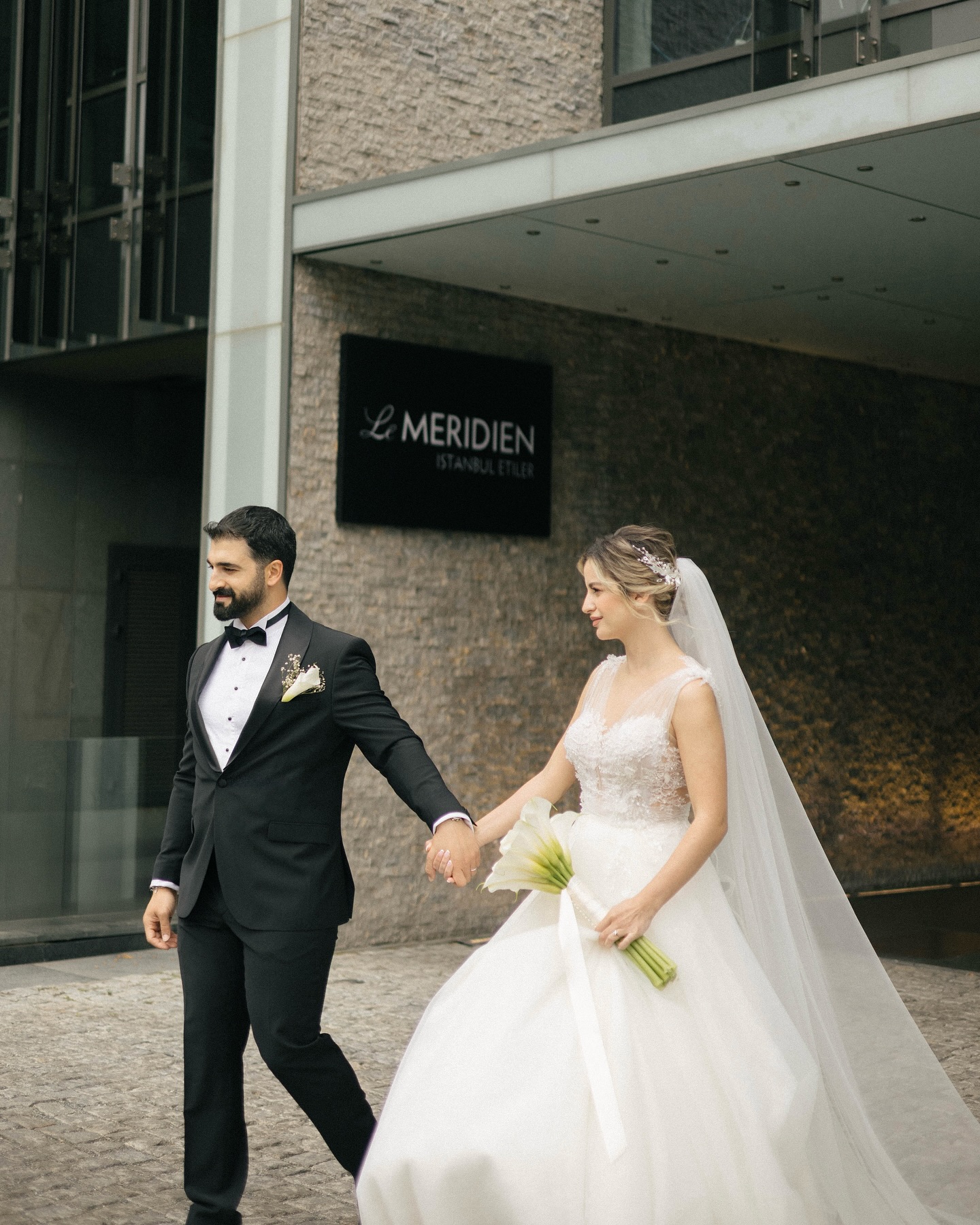 Damat ve gelinin düğün çekimi sırasında el ele yürüdüğü kare