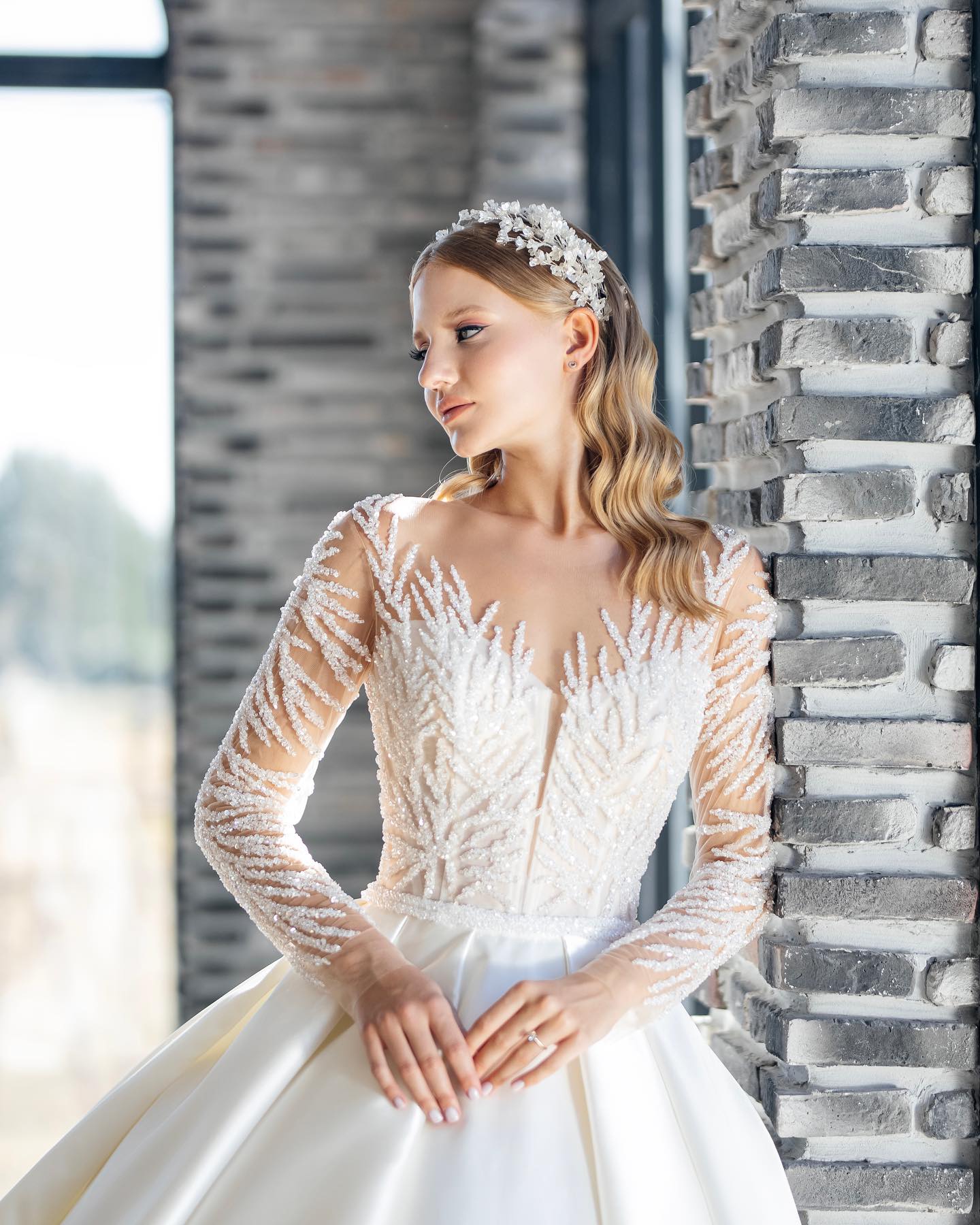 Transparan dantel üst ve sade saten etek gelinlik, tuğla duvar arka plan