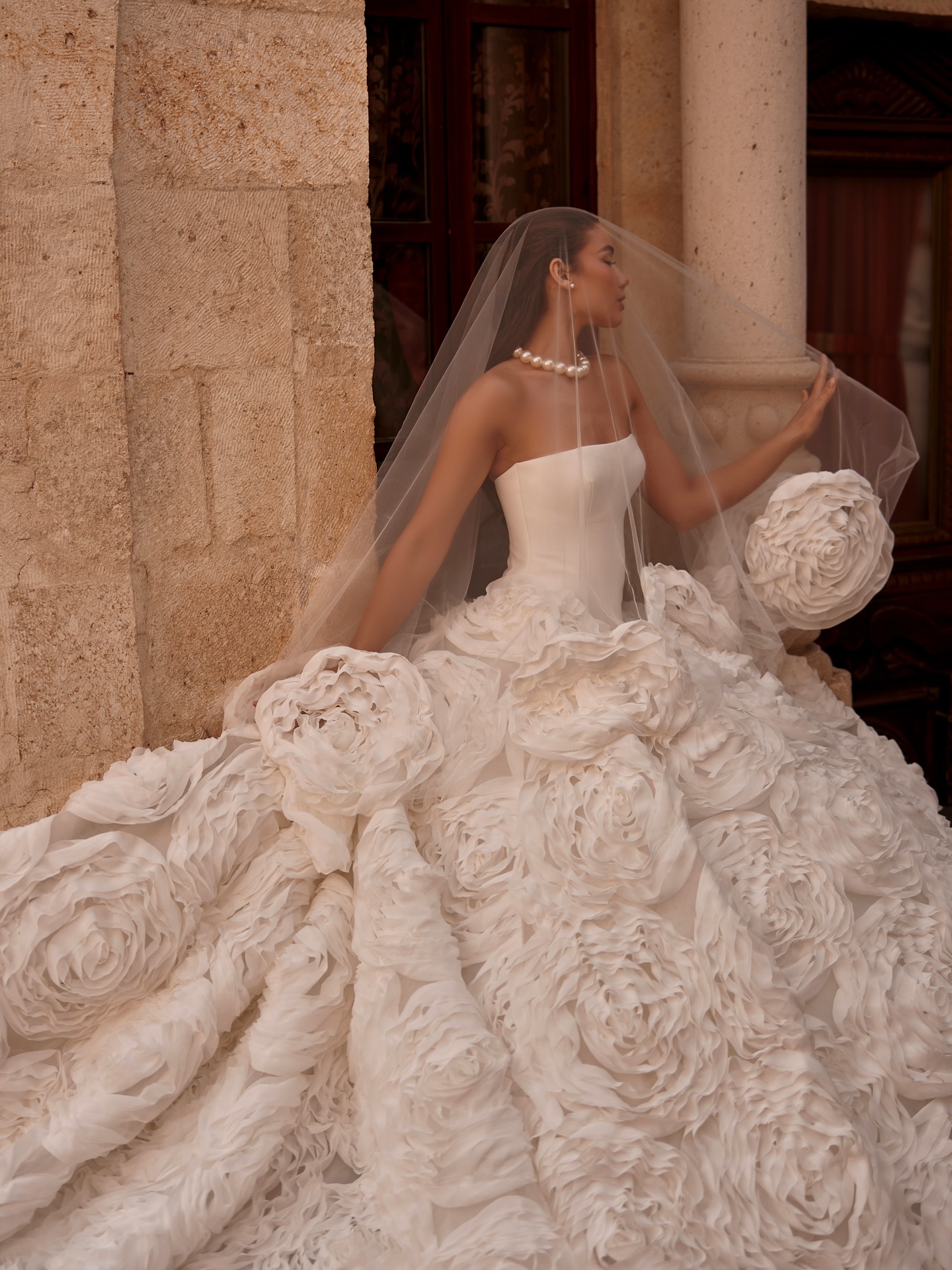 Yakın plan 3D gül dokulu couture gelinlik eteği ve straplez korsaj üst formu, duvakla birlikte zarif görünüm.