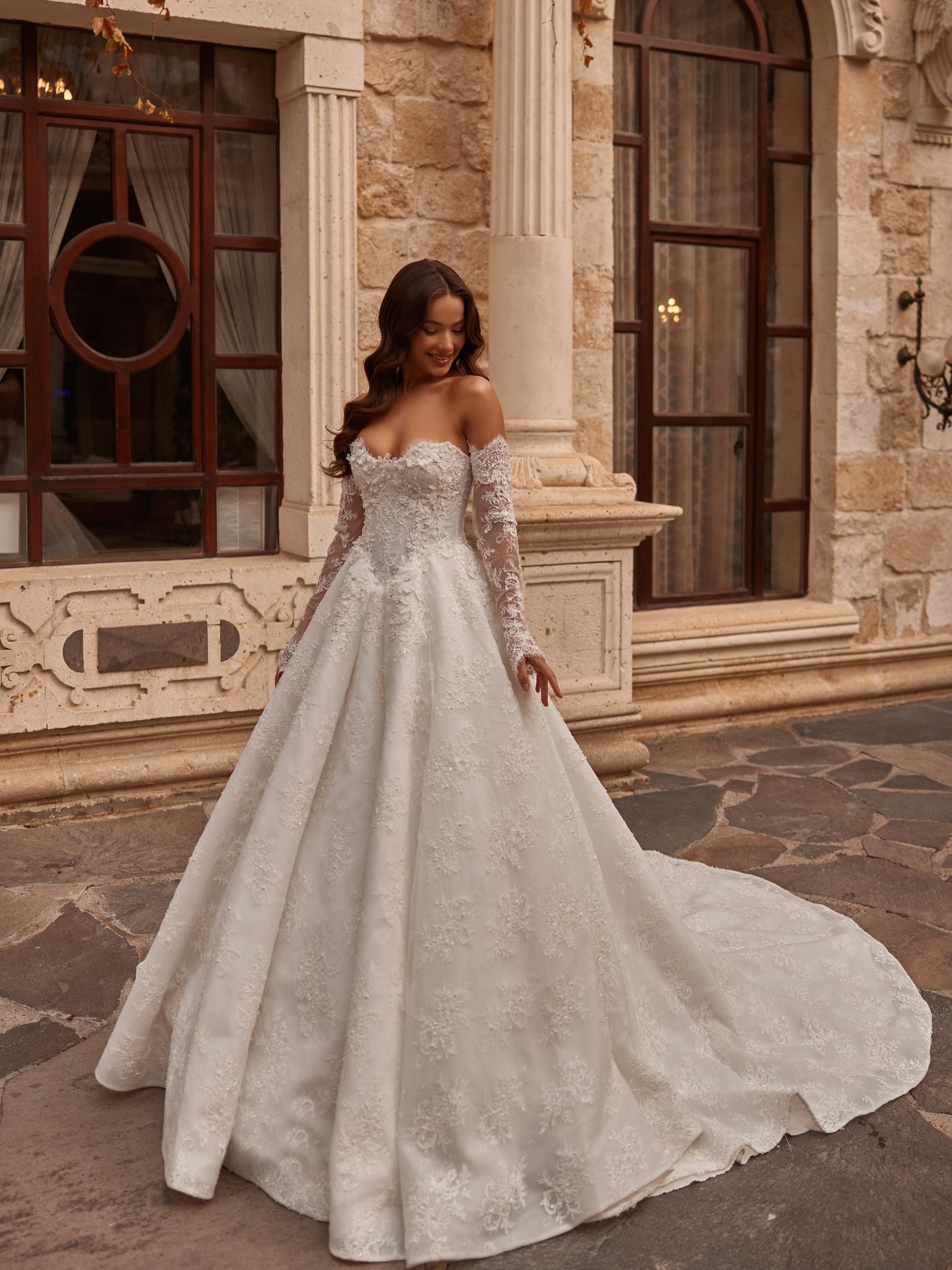 Düşük omuz kalp yaka, dantel işlemeli prenses gelinlik modeli ile dış mekânda romantik gelin pozu.