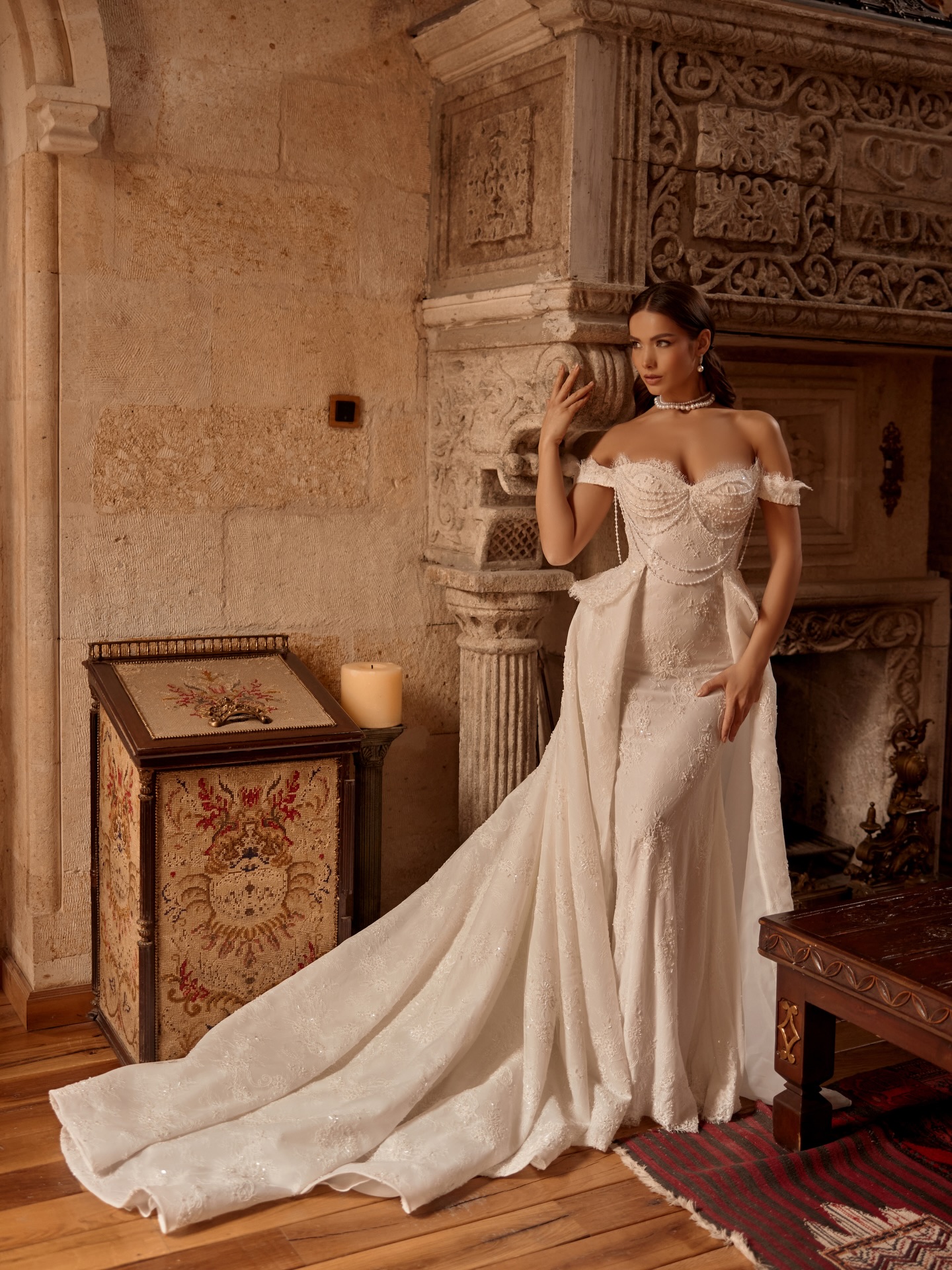“Düşük omuz inci drapeli balık gelinlik, romantik dantel dokusu ve sofistike duruşuyla tam boy çekim.”