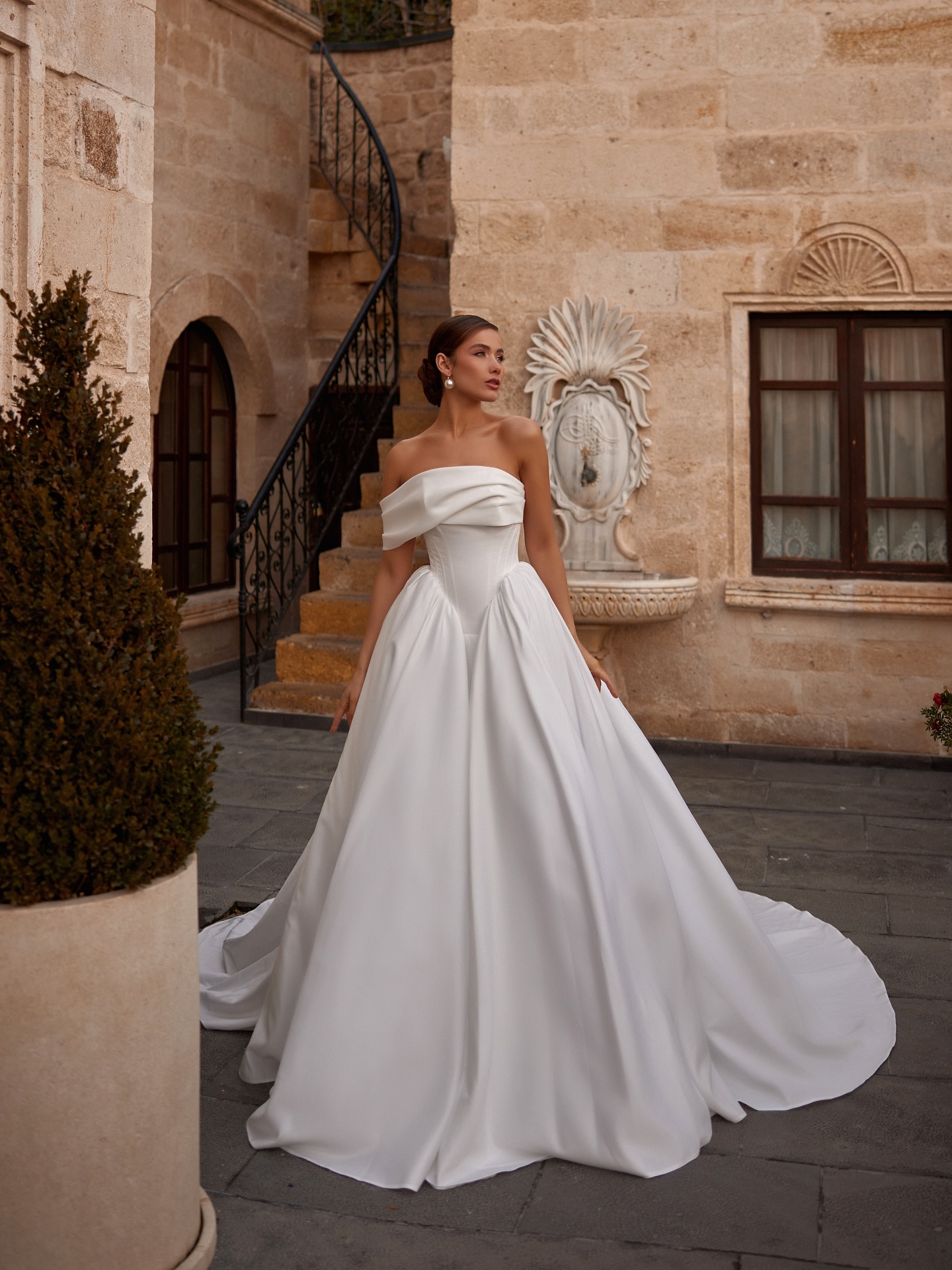 Straplez düşük omuzlu drapeli yaka detayıyla modern prenses siluetinde Mediha Cambaz Bridal gelinlik.