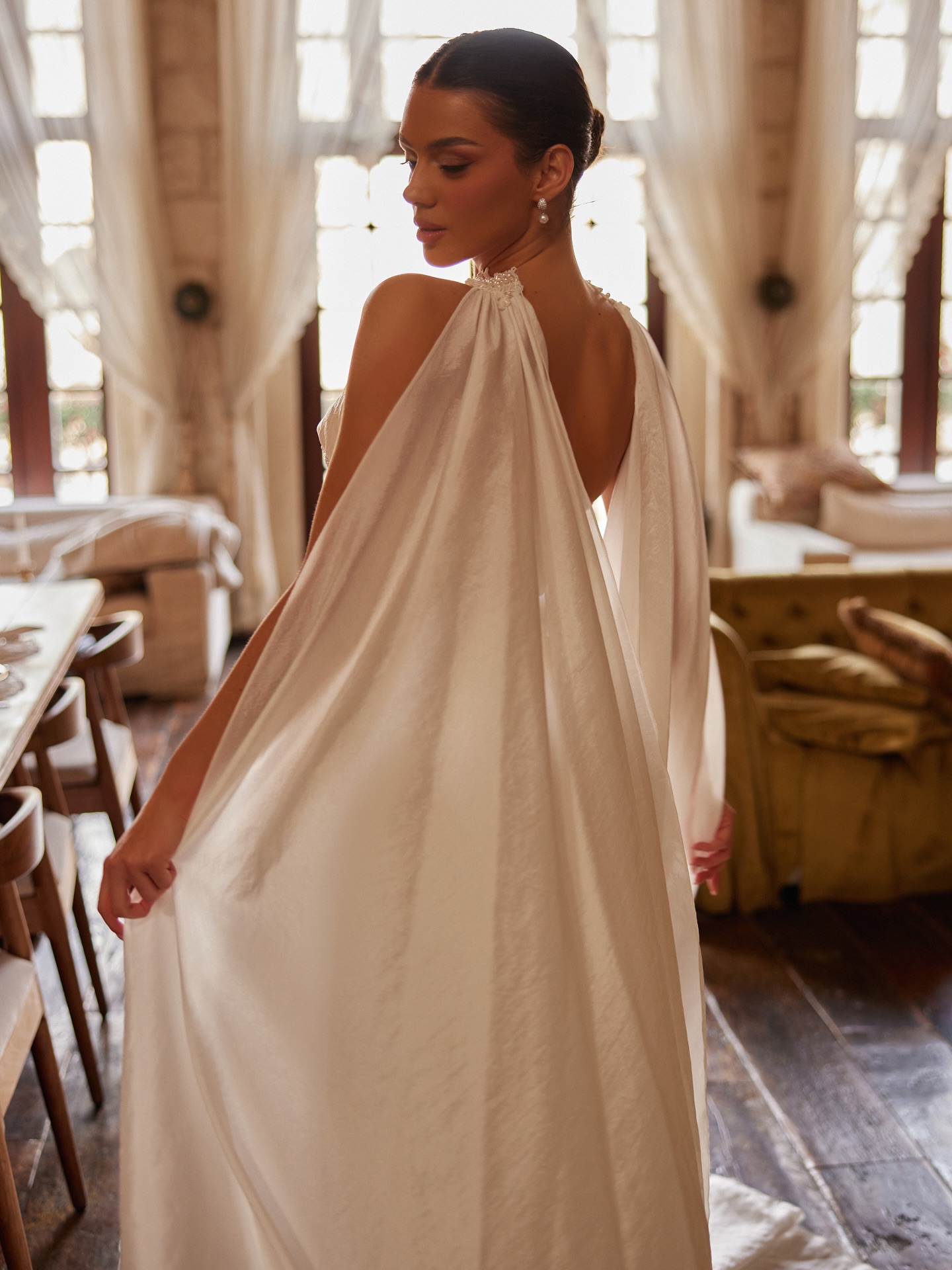 Straplez korse gelinliğin arkadan görünümü, omuzdan dökülen pelerin detayıyla modern ve zarif duruş