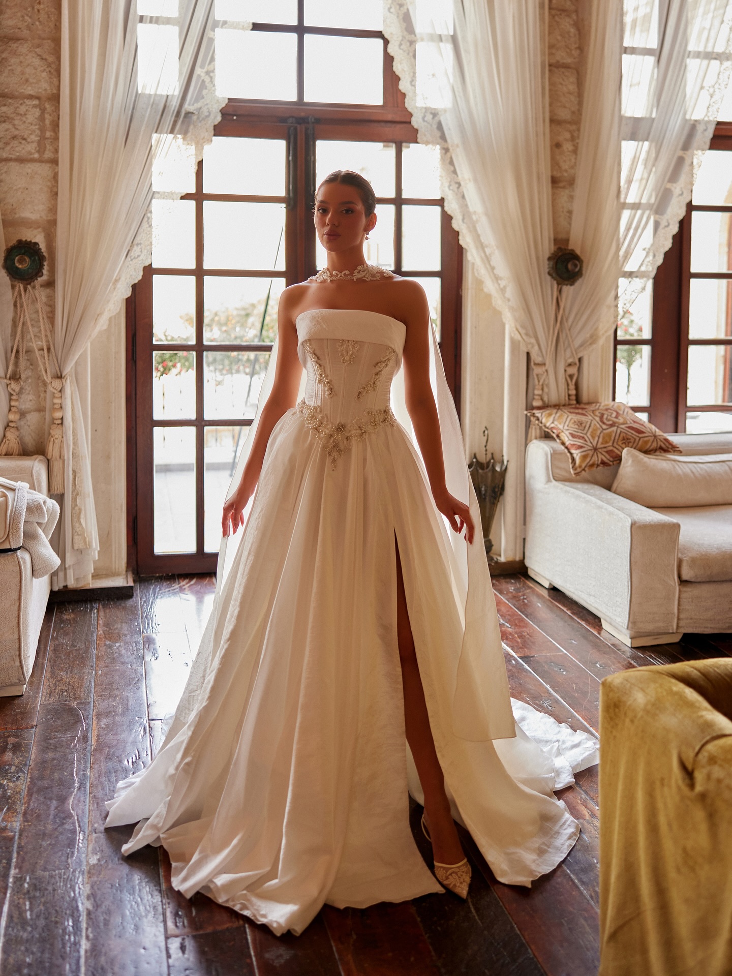 Tam boy görünümde yırtmaçlı straplez gelinlik, taş işlemeli bel detayı ve zarif etek hacmi