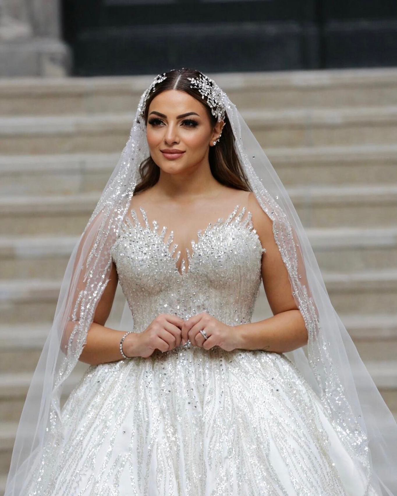 Taş işlemeli prenses gelinlik, derin V yaka ve ışıltılı duvak detayıyla önden yakın çekim