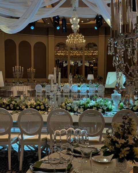 Uzun masa düzeninde cam şamdanlı romantik düğün dekorasyonu