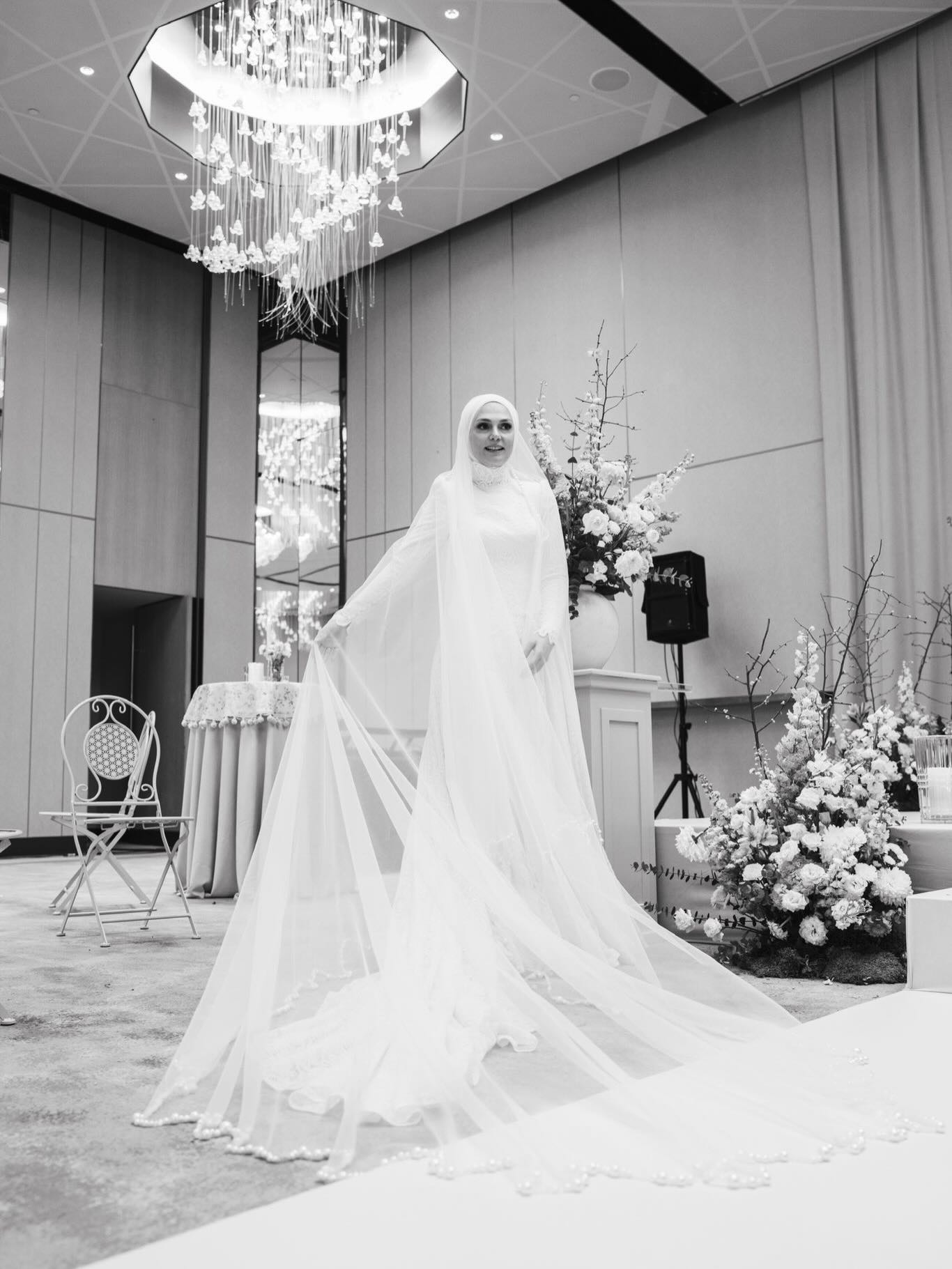 “Özem Keskin tesettür gelinlik, uzun duvak ve dantel etek – siyah beyaz salon düğünü çekimi”