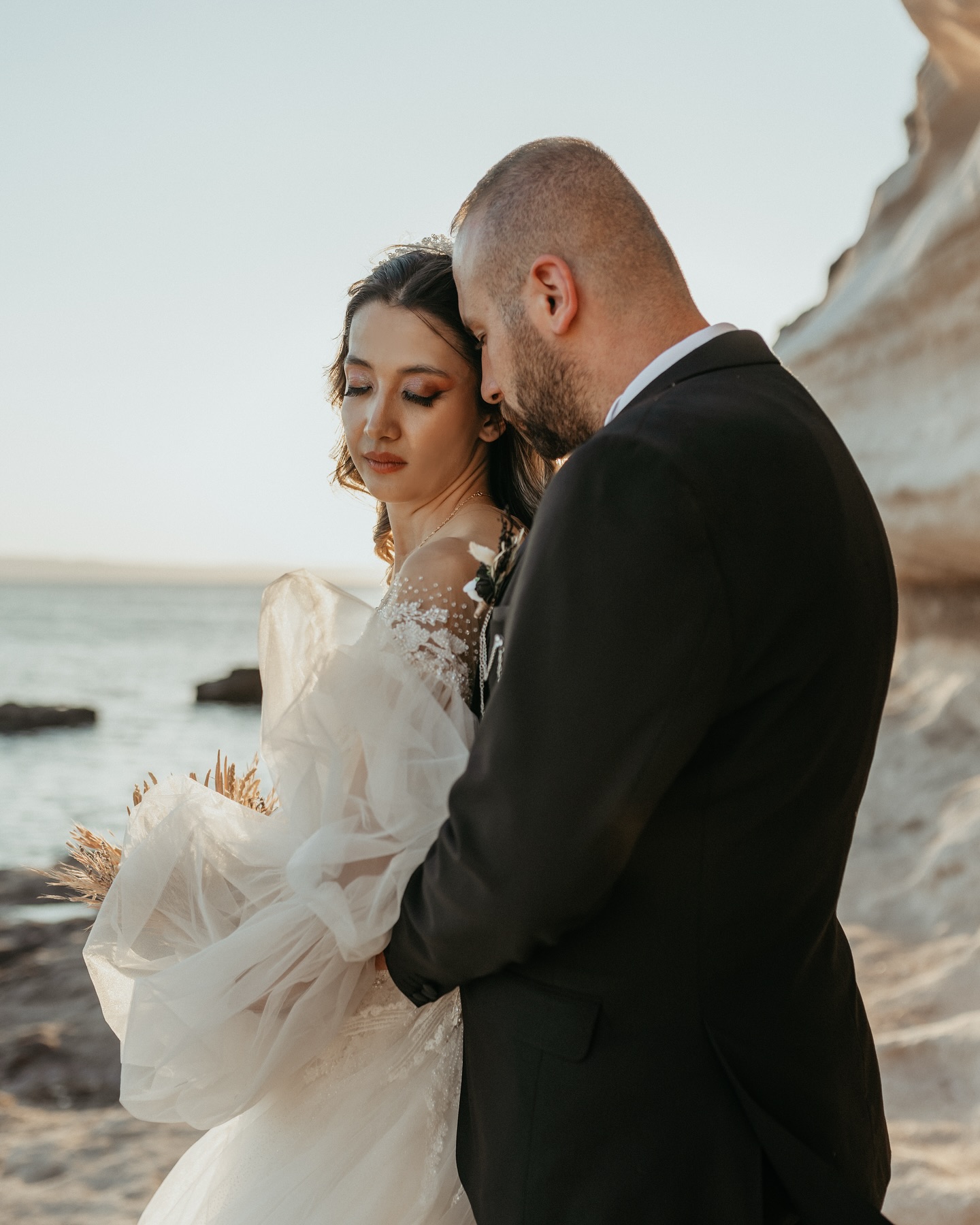 Sahil kenarında romantik çift pozu, tül kollu dantel işlemeli A kesim gelinlik detayı