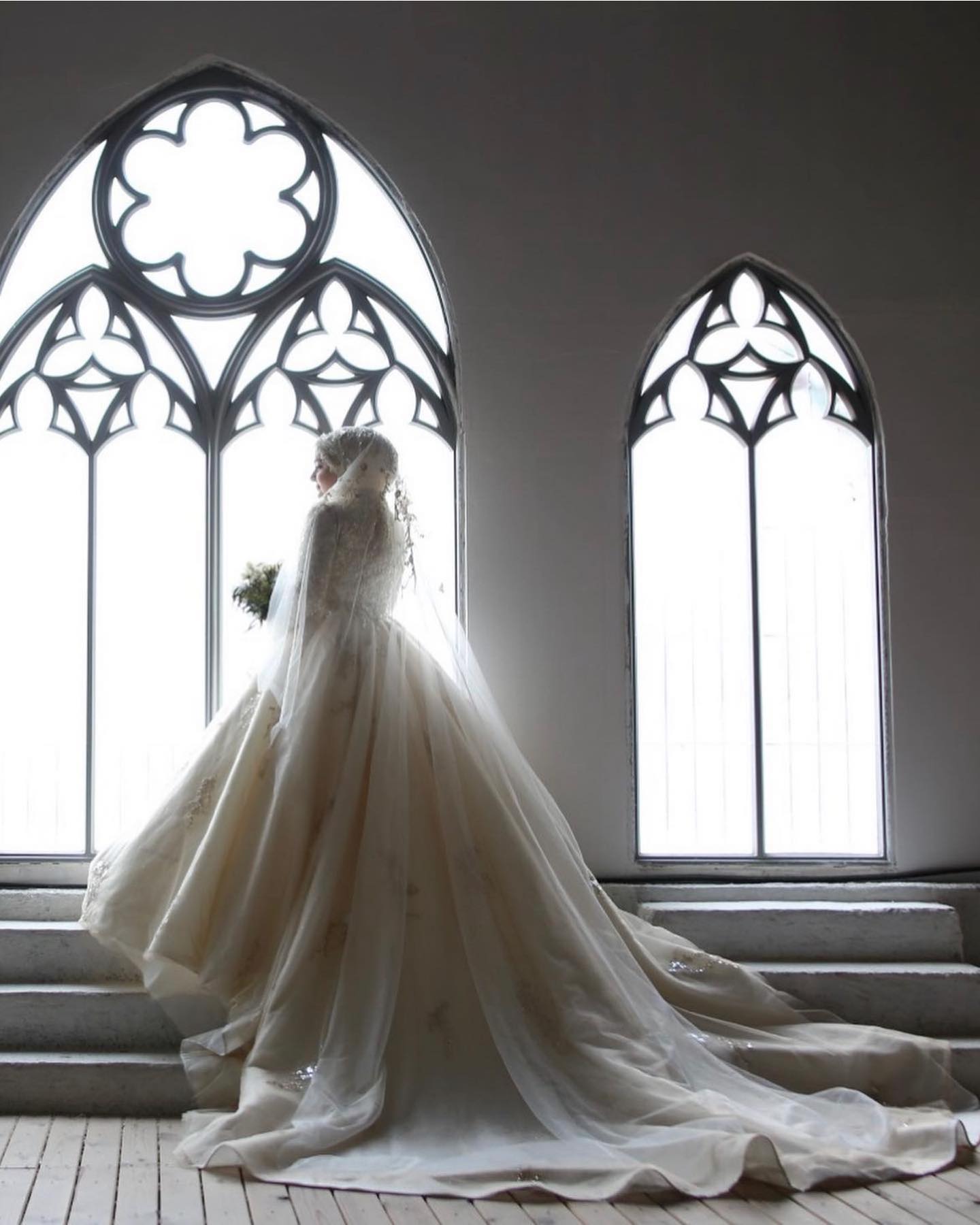 Prenses kesim kabarık gelinlik ve katedral duvak – gotik kemerli pencerede siluet