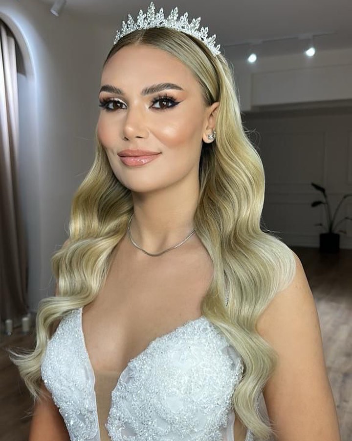 Taç ve Hollywood dalgası saçla V yaka dantel gelinlik – yakın plan gelin portresi