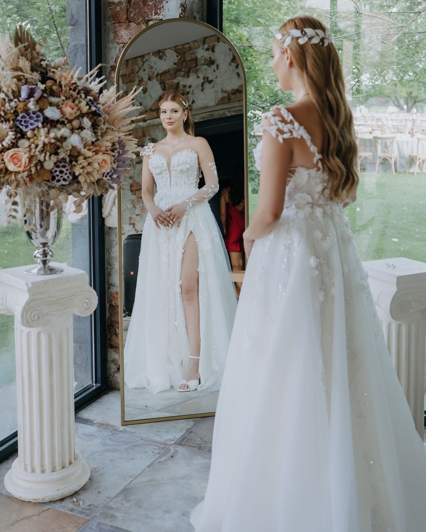 A kesim siluetli, 3D çiçek işlemeli ve derin V yakalı gelinlik ile aynada poz veren gelin