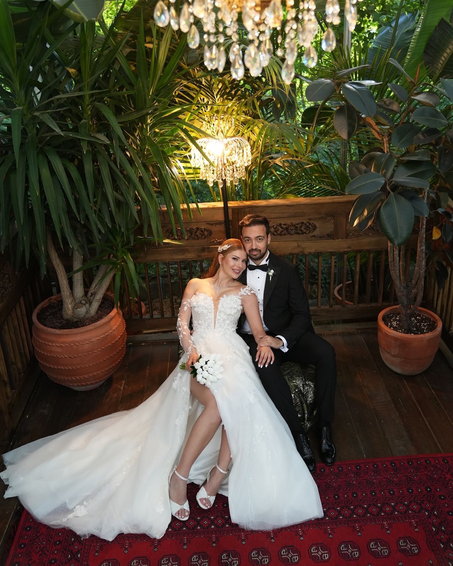 3D çiçek detaylı A kesim gelinlik giyen gelin ve damadın romantik oturma pozu, uzun kuyruk detayı