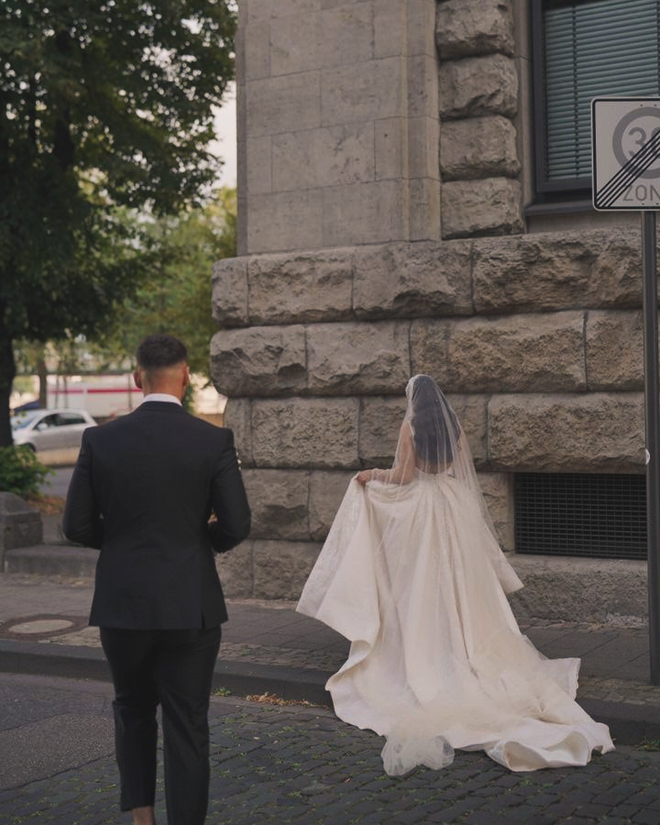 “Gelinliğin arkadan görünümü: uzun kuyruk, sade duvak ve geniş etek hacmiyle masalsı siluet.”